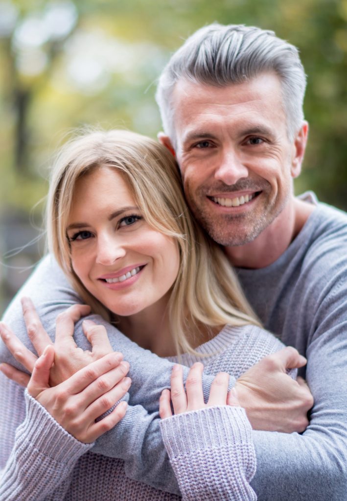 Loving couple hugging outdoors and looking happy