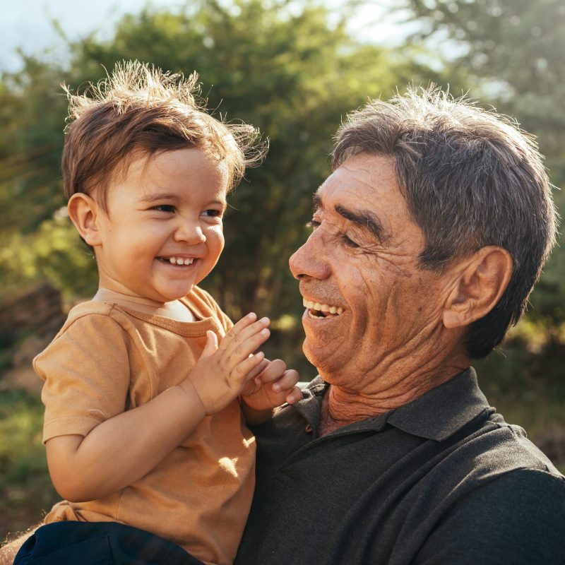 Playful grandfather spending time with his grandson in park on sunny day