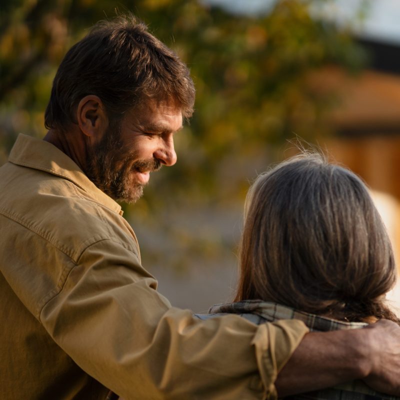 A rear view of mature couple looking at their new house under construction, planning future and dreaming.